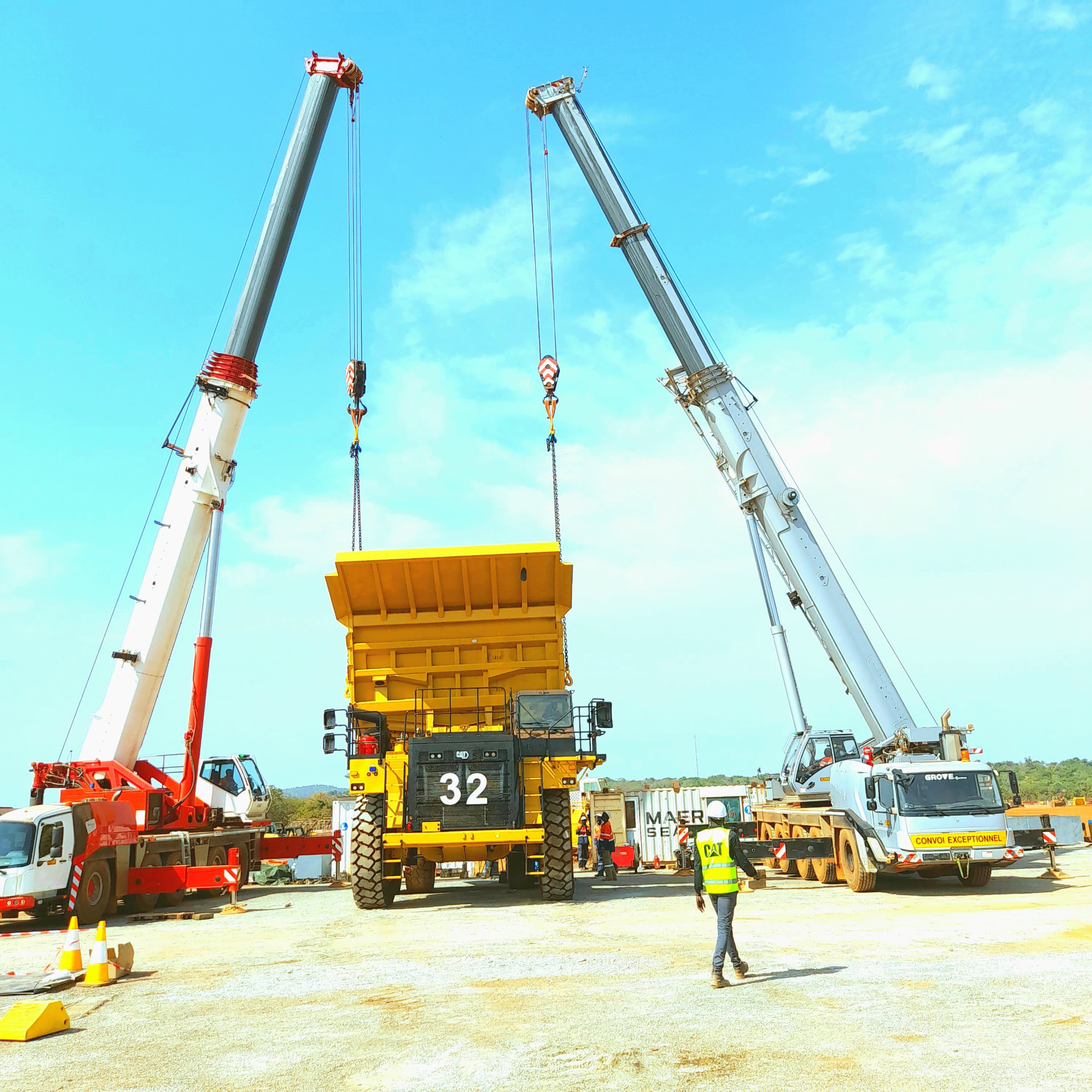 Deux grues mobiles procédant au levage synchronisé d'une benne de tombereau minier